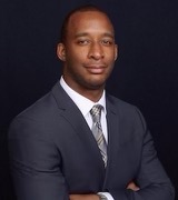 A man in a suit and tie standing with his arms crossed.