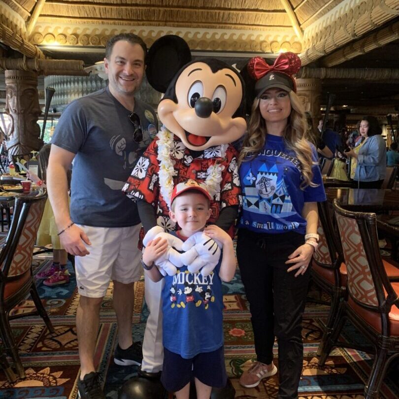 A family posing with mickey mouse and minnie mouse.